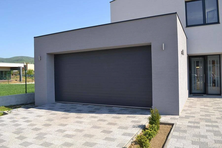 Modernes Haus mit breitem Garagentor in Grau und gepflasterter Einfahrt
