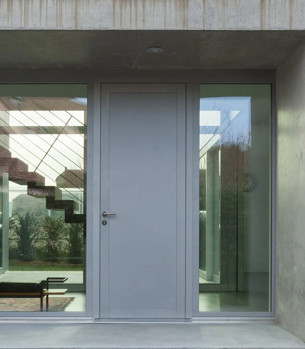 Moderne Haustür aus Metall mit großen Glasfenstern, Blick ins Treppenhaus